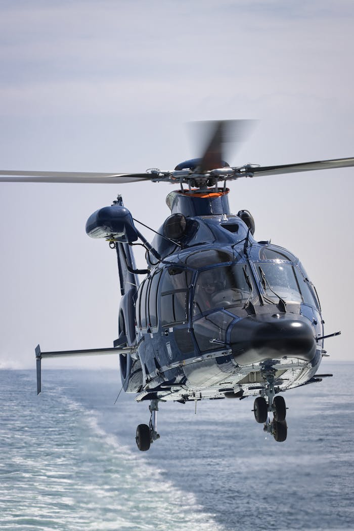 Dynamic shot of a helicopter flying above the ocean, showcasing motion and speed.