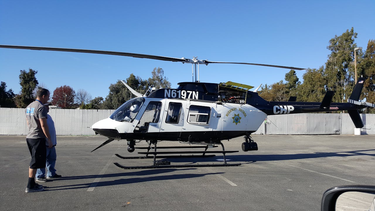 heros-img Police helicopter on display with officers standing beside it in an outdoor setting.