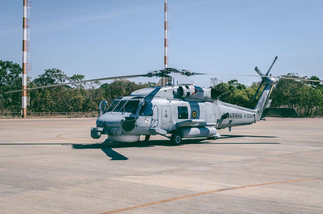 about-us-01 Military helicopter stationed at BrasÃlia airstrip with clear blue sky background.
